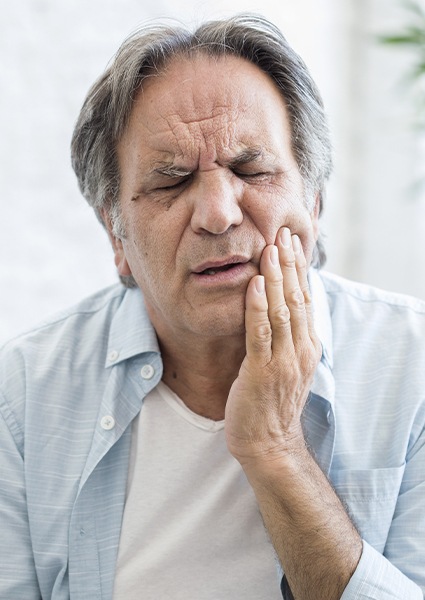 Man experiencing T M J problems holding jaw in pain
