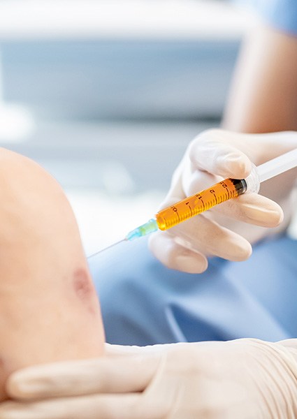 Doctor administering ultrasound-guided injection into patient’s knee