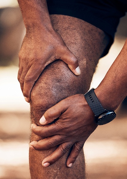 Man gripping his knee, experiencing arthritis pain
